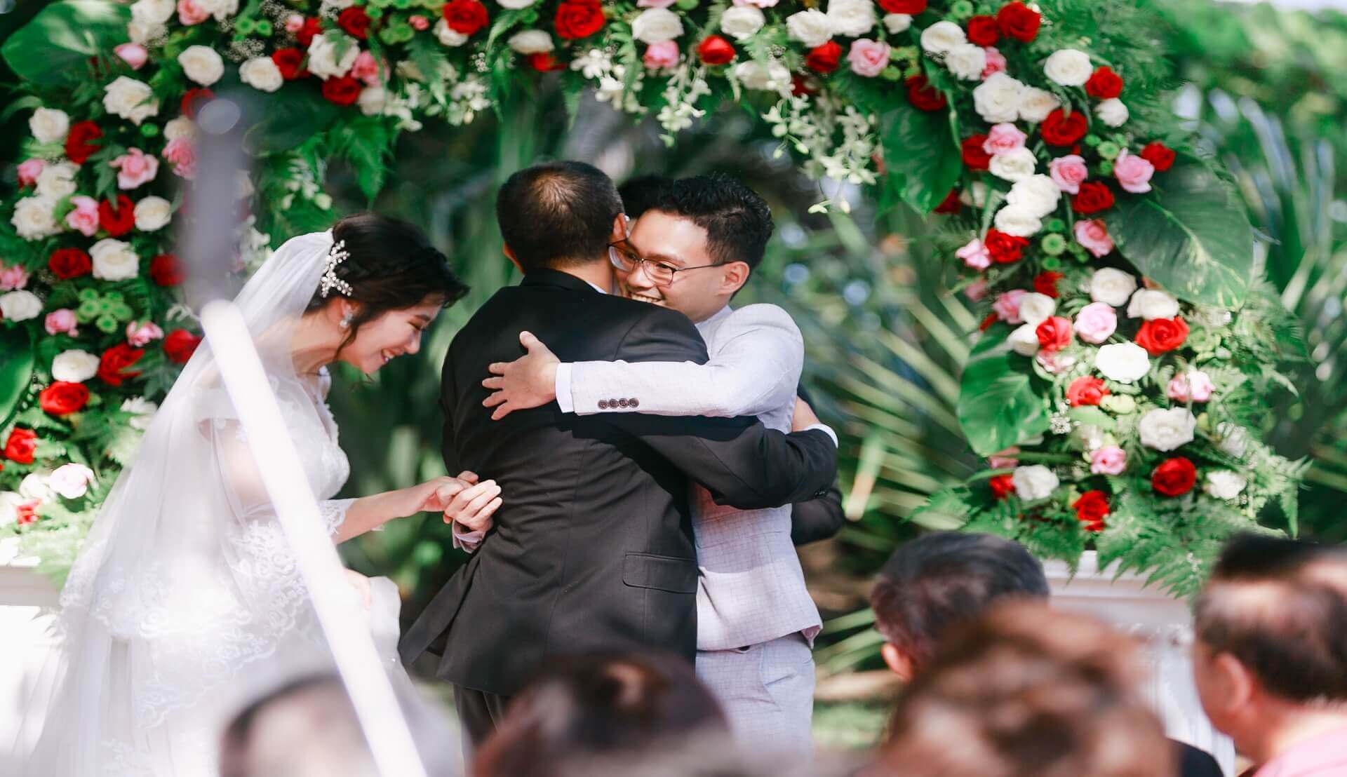 Sugar & Spice Events - Wedding couple hugging parent under flower arch