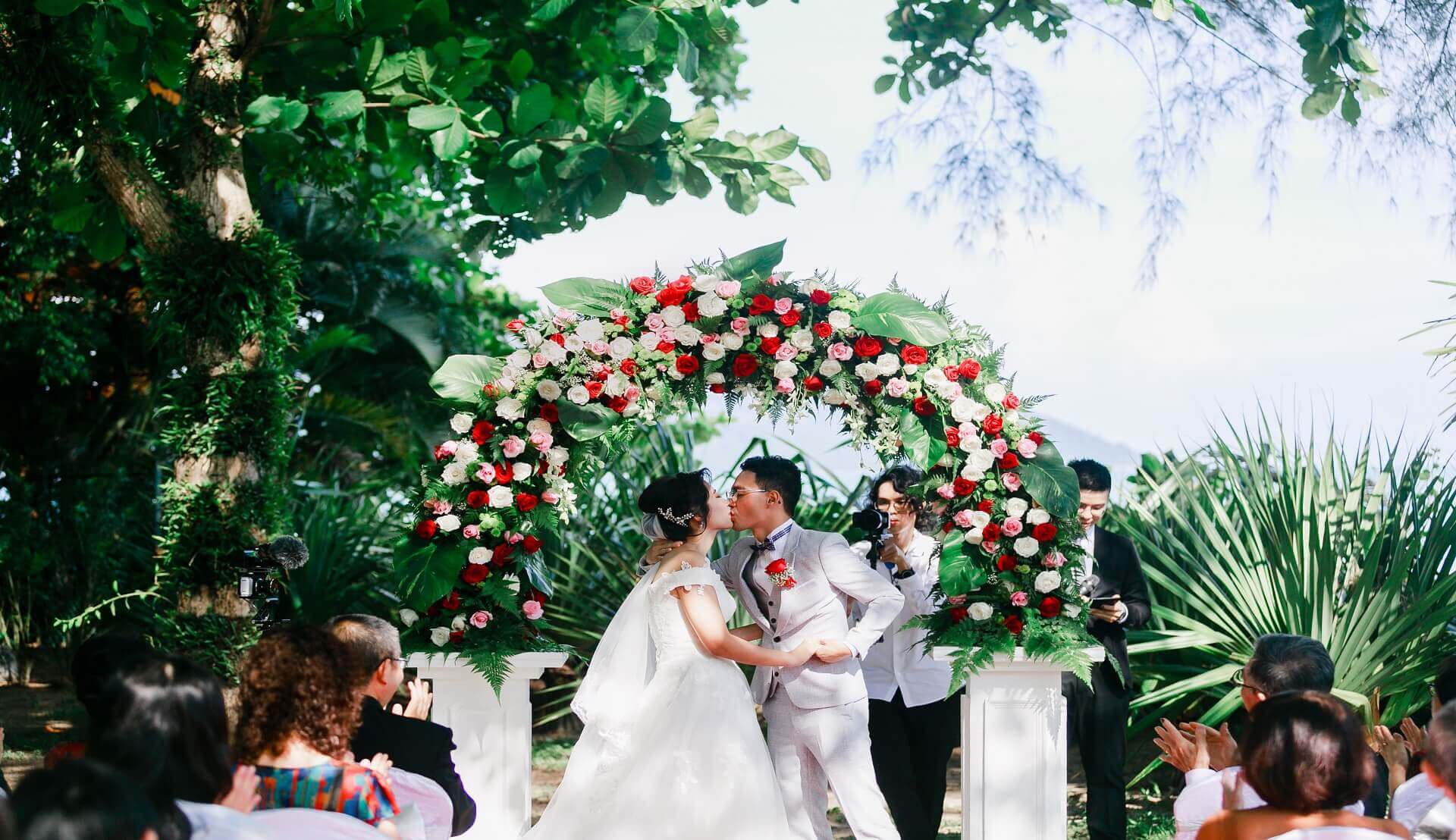 Sugar & Spice Events - Newlywed couple dip kiss outdoor ceremony flowers garden wedding beach floral arch